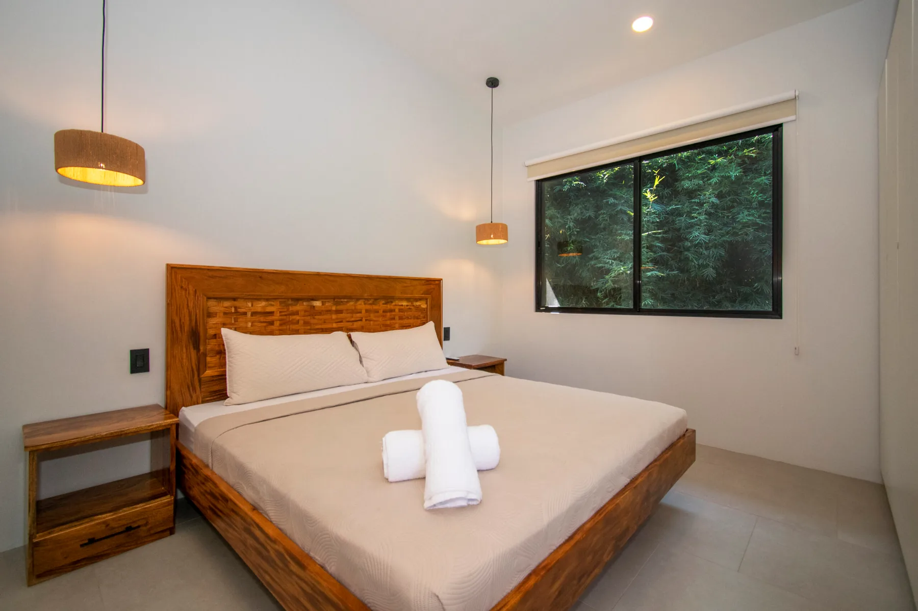 Un dormitorio con una cama de madera y una ventana grande con vistas a la vegetación.