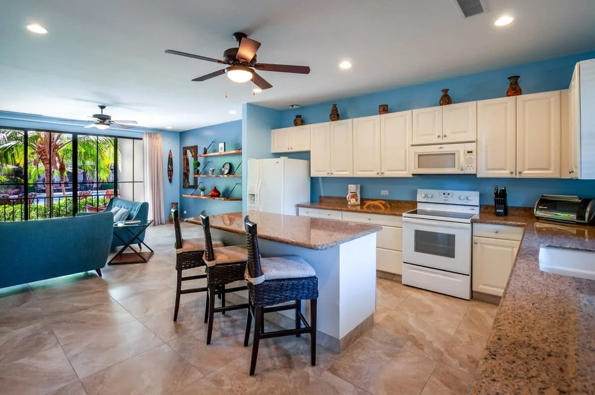 Una cocina y comedor abiertos con una isla central y paredes azules.