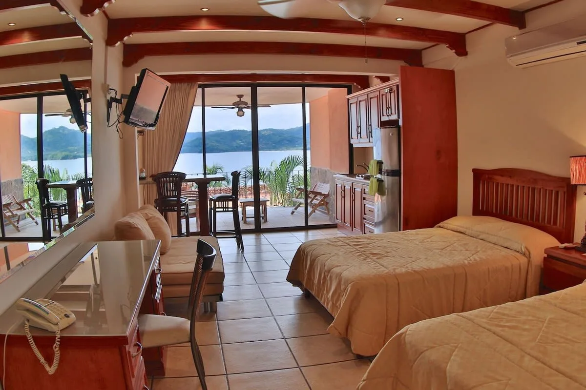 Un dormitorio con dos camas y puertas corredizas de vidrio con vista al agua.