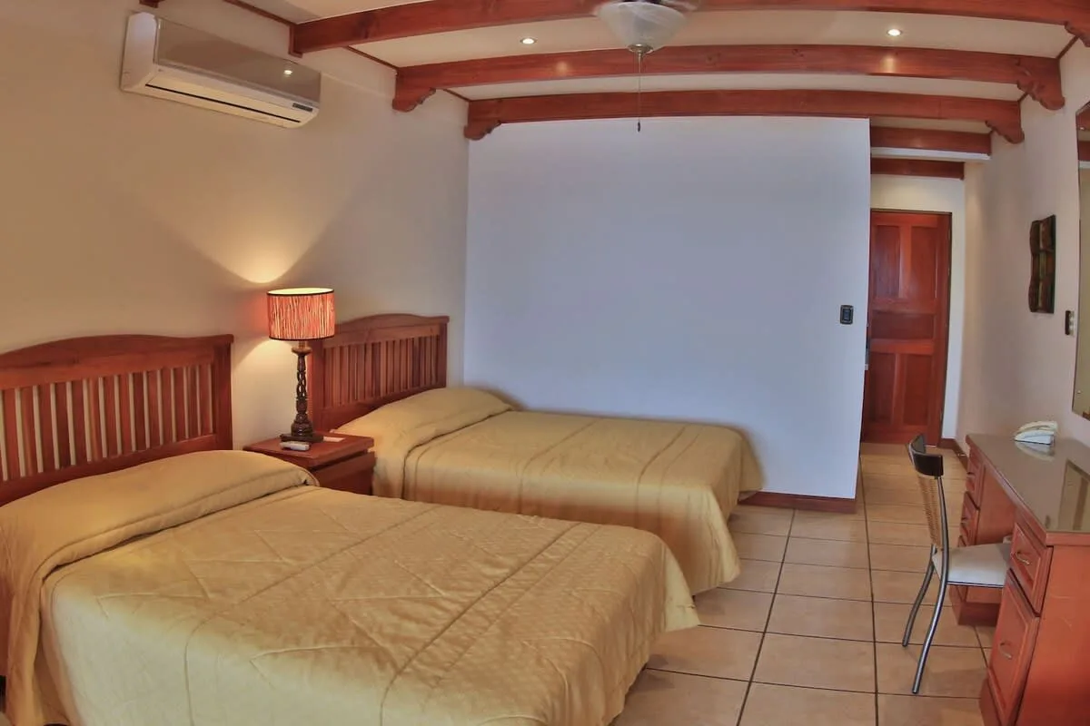 Un dormitorio con dos camas, cabeceros de madera y una pequeña mesita de noche.