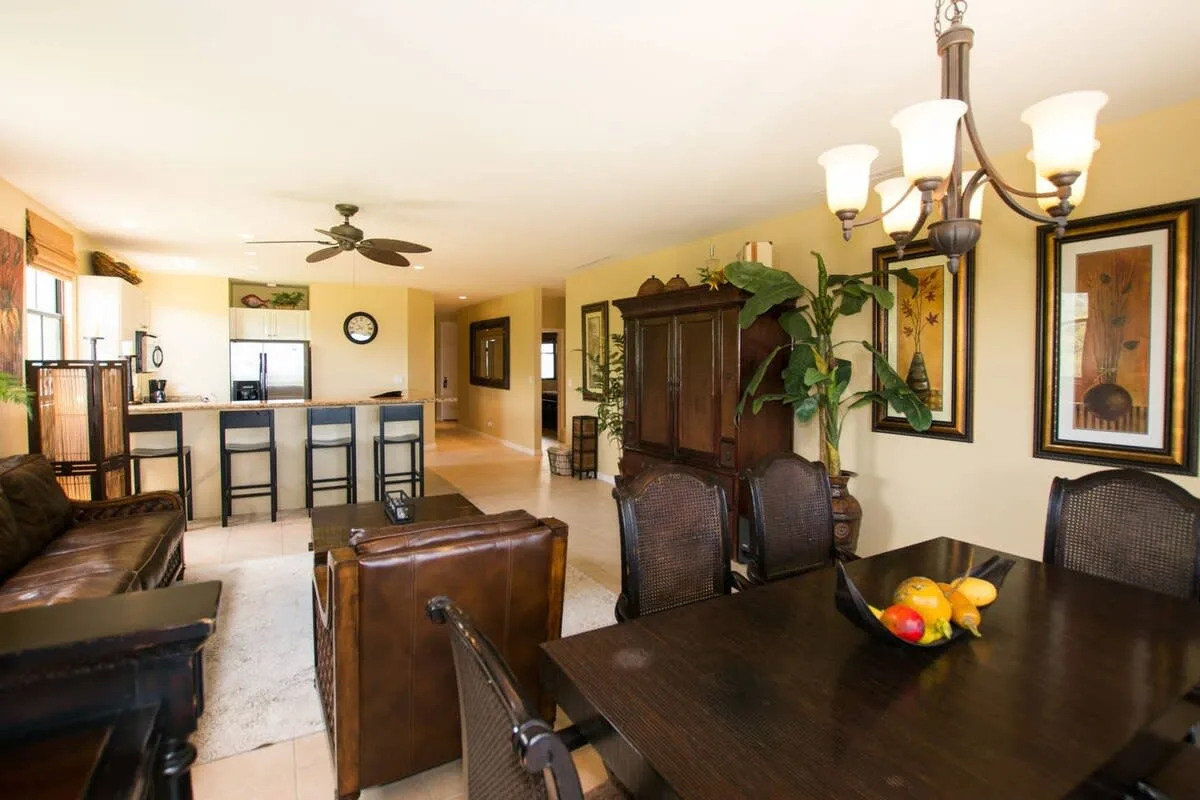 An open-plan dining and living area includes a dining table and kitchen counter.