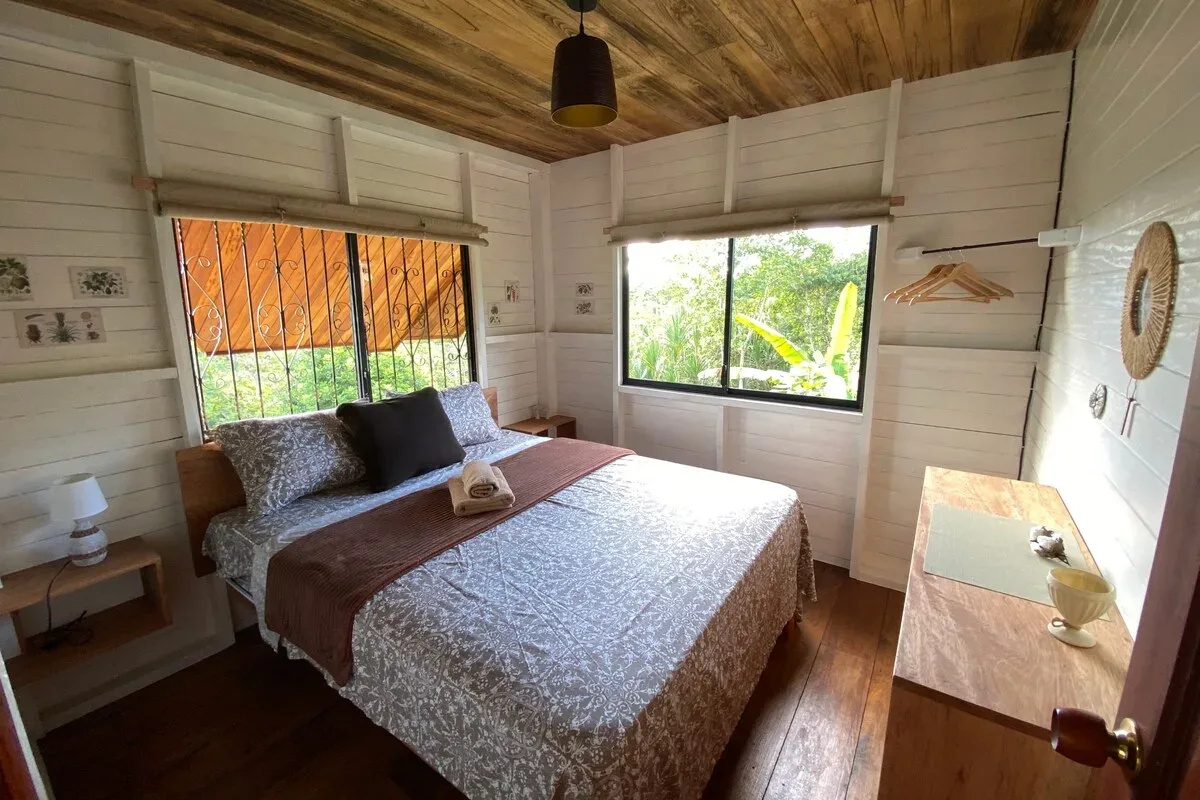 Dormitorio con cama queen y vistas al jardín