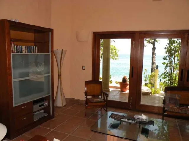 A living room opens onto a patio with a view of the sea.