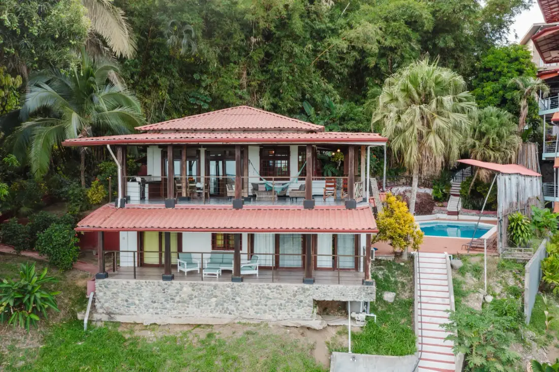 Casa Blue Wind · 30. A two-story villa with red tile roofs features open-air terraces on both levels and a private pool, surrounded by dense tropical greenery.