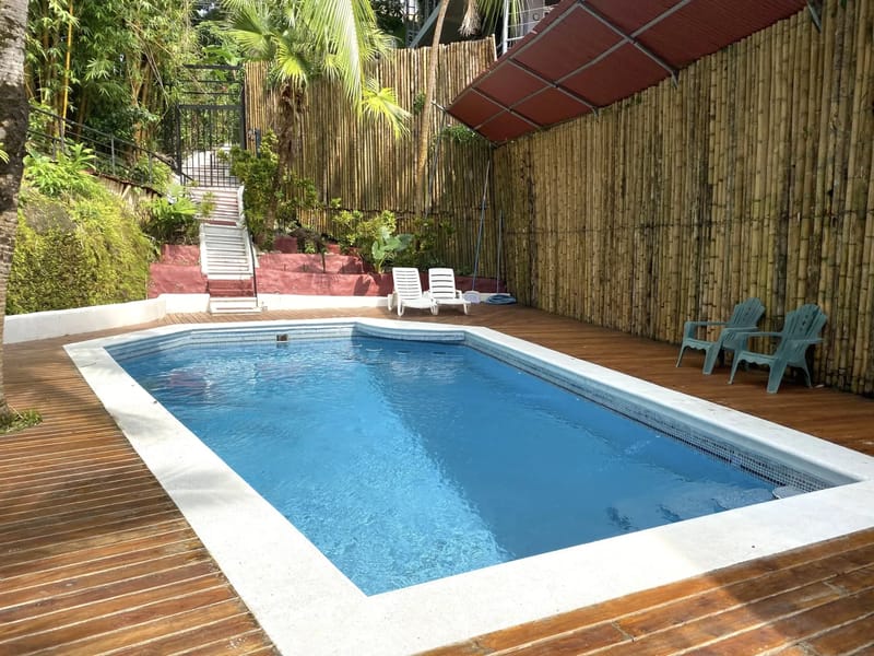 Casa Blue Wind · 5. The outdoor swimming pool area features a wooden deck, a tall bamboo fence, and abundant tropical foliage providing natural privacy.