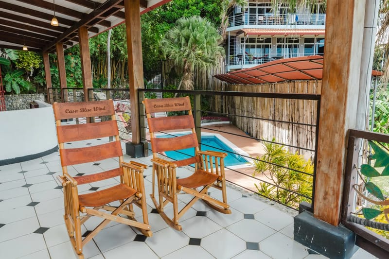 Casa Blue Wind · 12. A covered terrace with a tiled floor and wooden support beams offers a comfortable seating area with views of the private pool and lush tropical gardens.