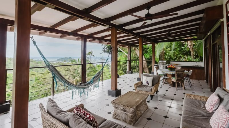 Casa Blue Wind · 21. An open-air covered terrace offers a spacious lounge and dining area with an outdoor kitchen, featuring a hammock and expansive views of the ocean and surrounding tropical forest.