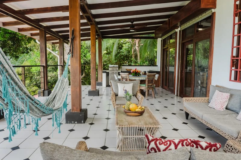 Casa Blue Wind · 6. This spacious, covered outdoor terrace features an open-air living and dining area with wooden structural elements, tiled flooring, and views of tropical foliage.