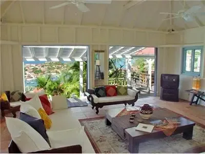 Una sala luminosa con asientos alrededor de una mesa baja y vistas abiertas al jardín.