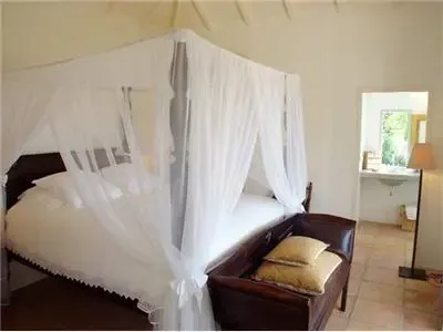 Un dormitorio con una cama con cortinas y un banco acolchado al lado.