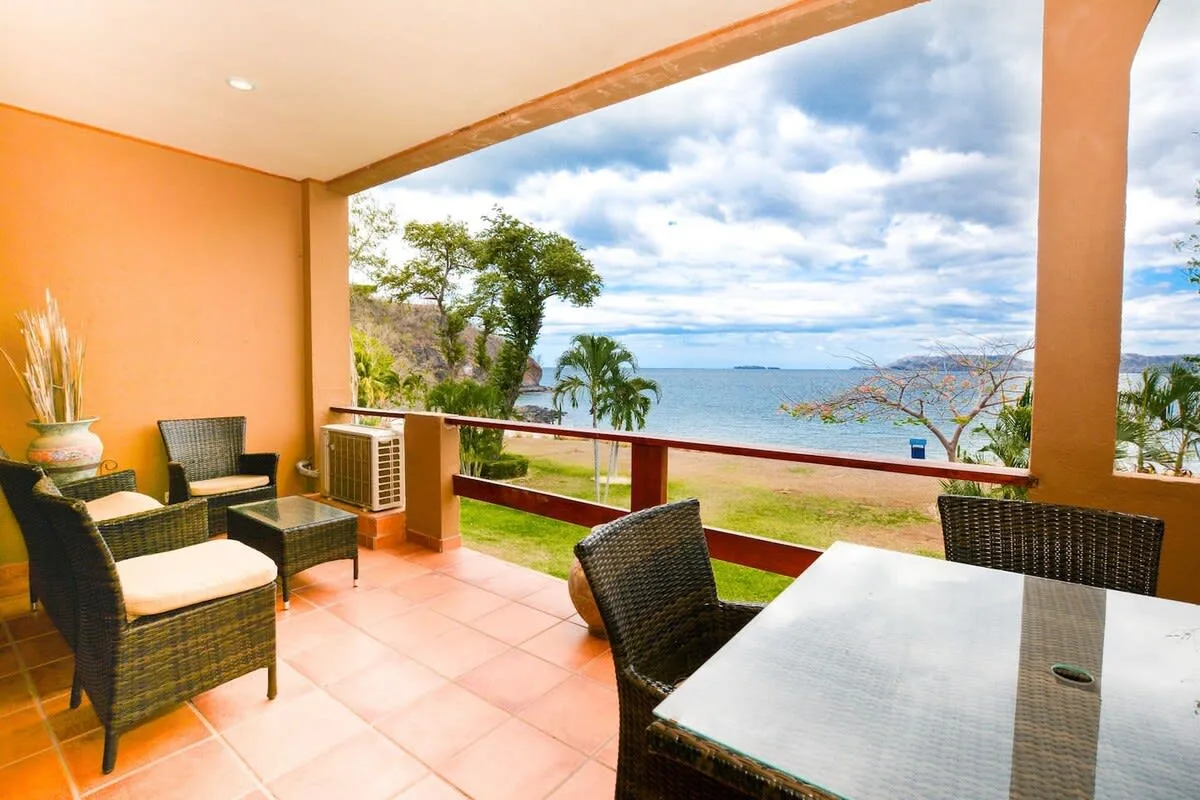 A covered patio with outdoor seating overlooks the water.