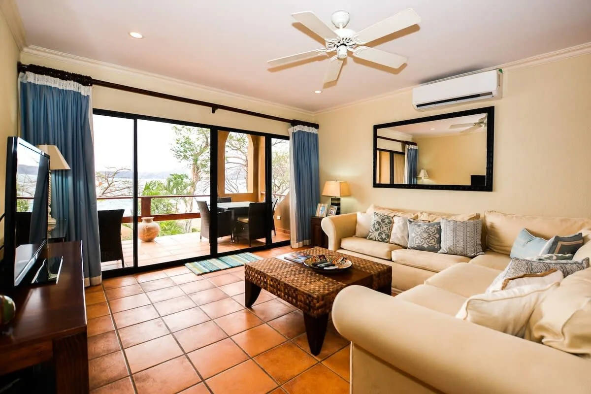 A living room with seating, a coffee table, and sliding glass doors opening onto a balcony.