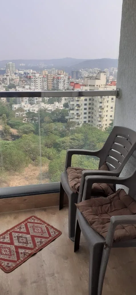 Una zona de estar en el balcón ofrece vistas de árboles y del perfil urbano a lo lejos.