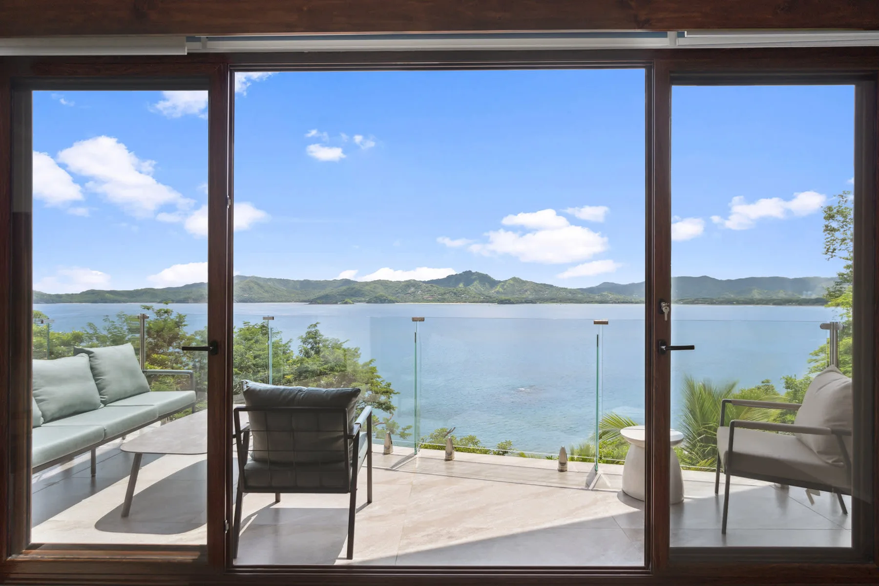 A lakeside patio with seating overlooks the water and distant hills.