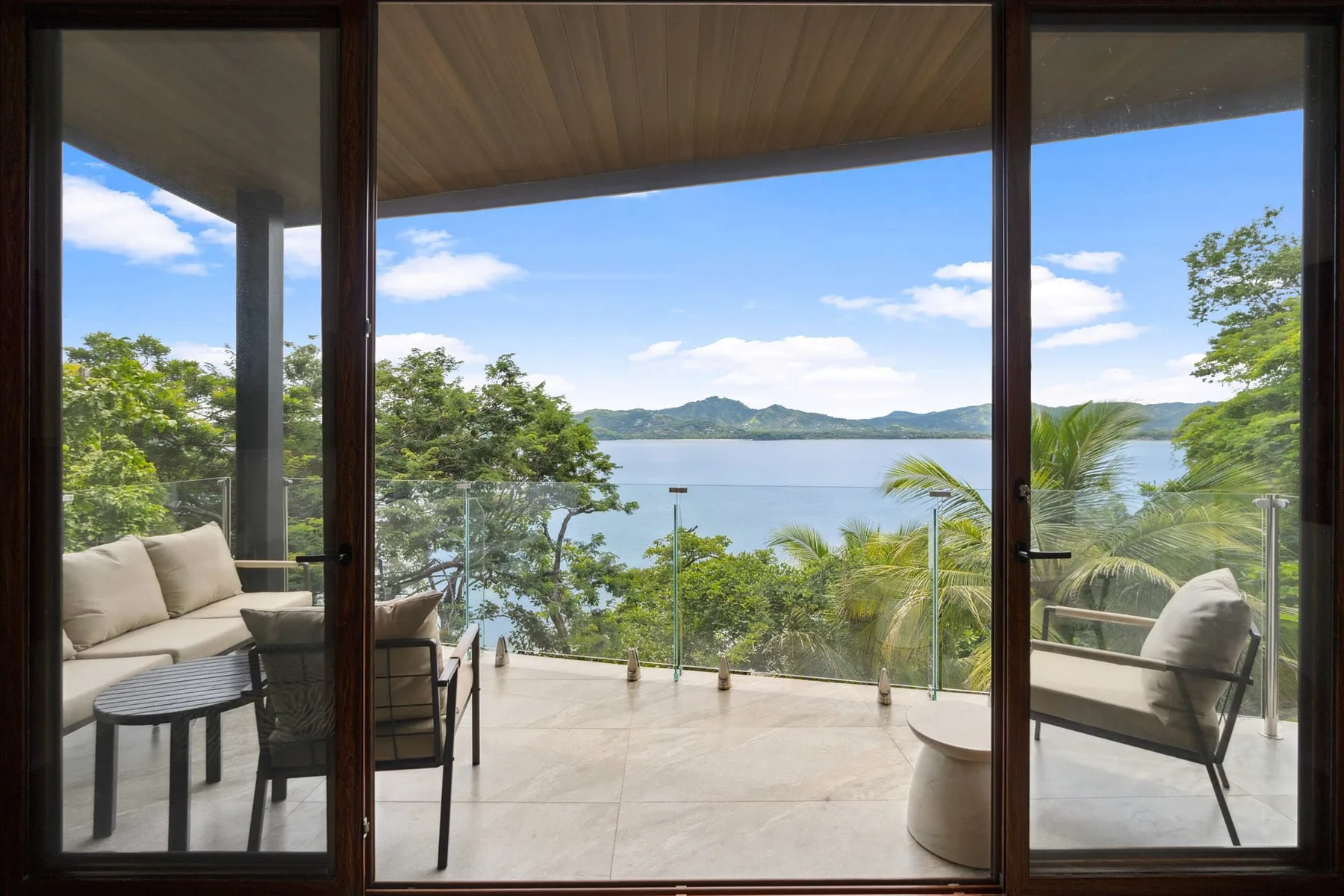A lakeside terrace with outdoor seating overlooks the water and distant hills.