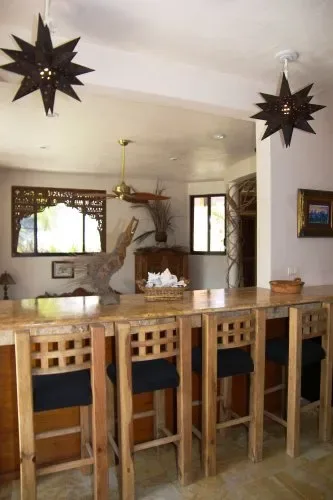 A dining area with a long wooden counter and tall stools beneath hanging star-shaped lights.