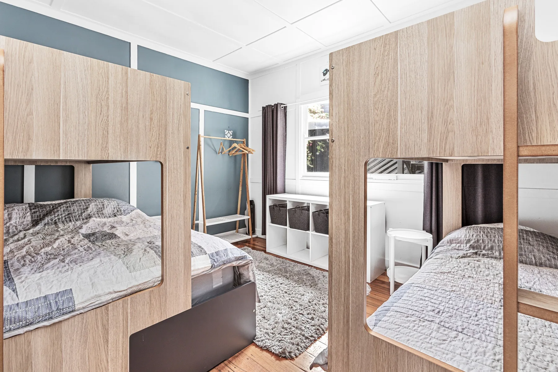 Un dormitorio con una cama, armarios y una ventana junto a una pequeña zona de escritorio.