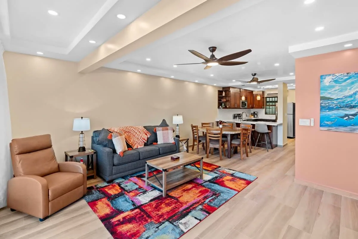 Living room with seating, a colorful rug, and a dining area beyond.