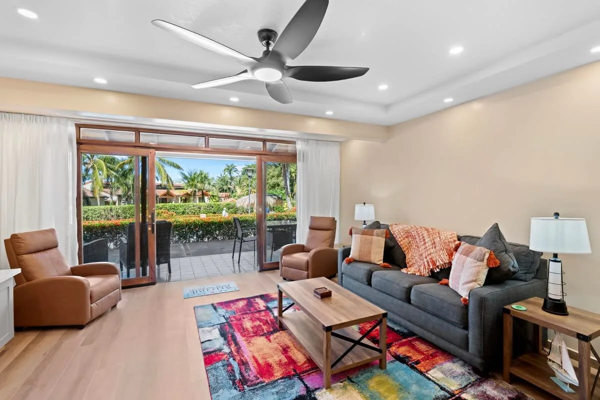 A living room with seating arranged around a coffee table and colorful rug.