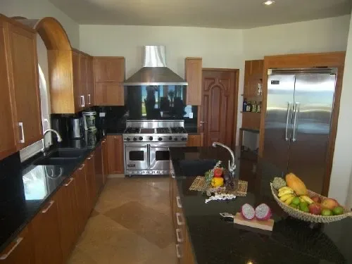 Una cocina con gabinetes de madera, electrodomésticos de acero inoxidable y una encimera oscura.