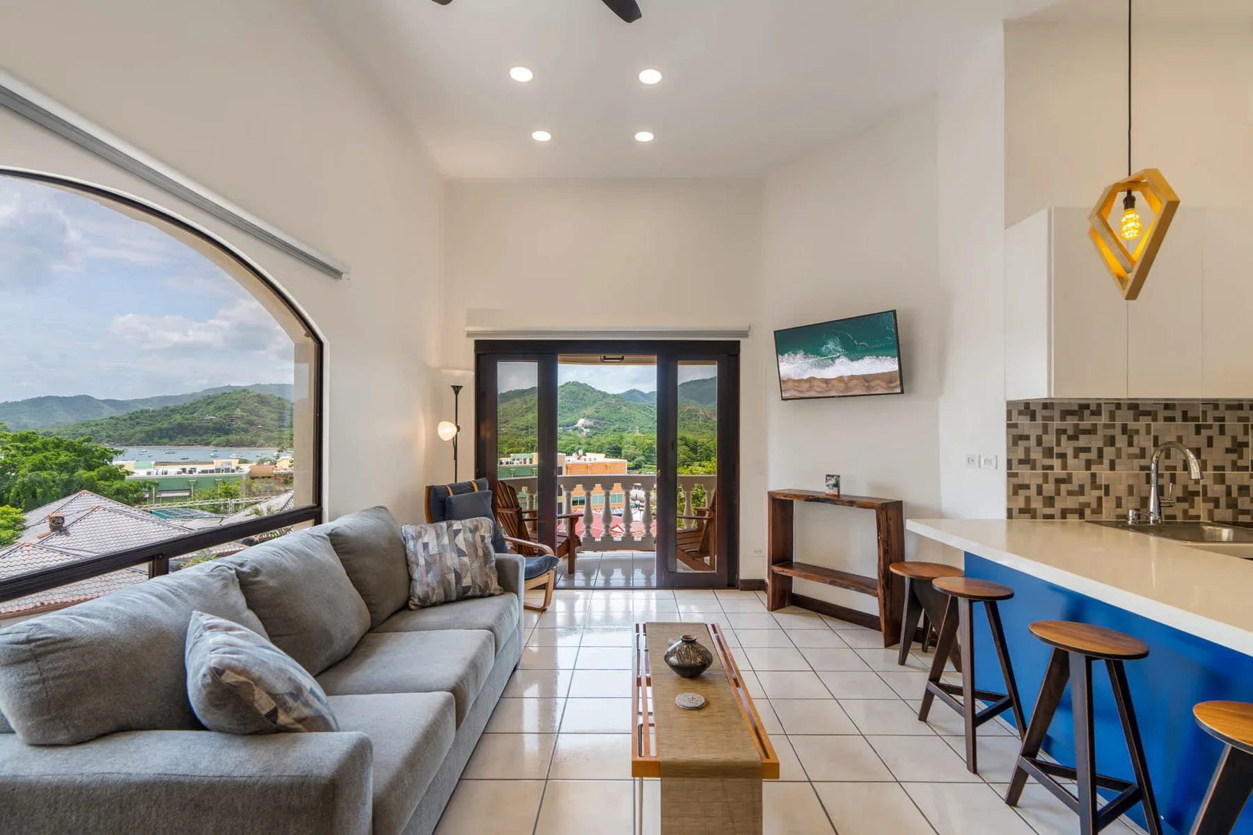 A bright living and dining area with a gray seating area and a counter with stools.