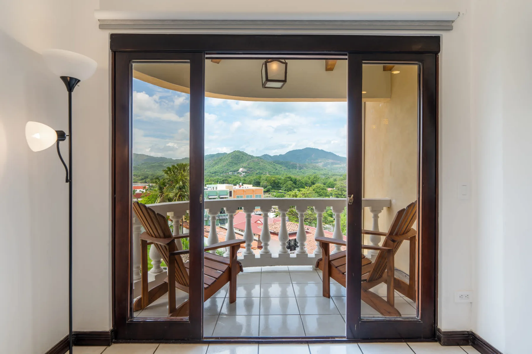 Sliding glass doors open onto a balcony with seating and a mountain view.