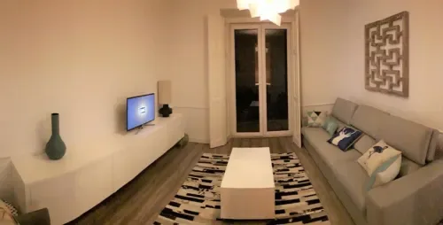 Una sala de estar con asientos, un televisor y una mesa de centro.