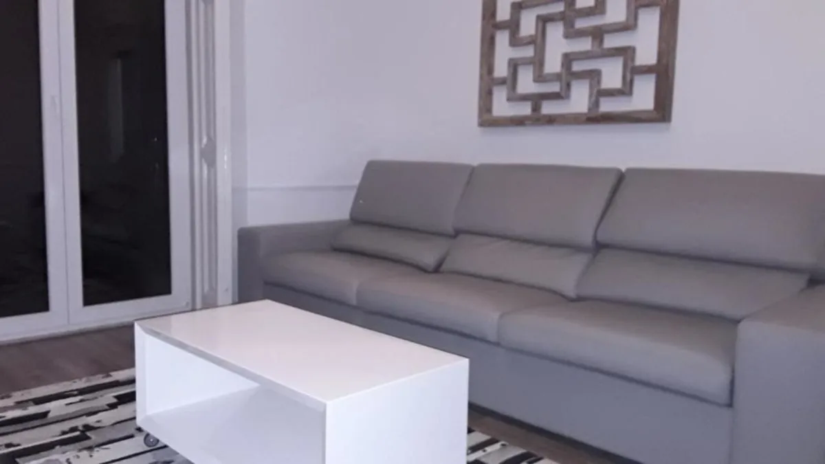 Una sala de estar con asientos grises y una mesa de centro blanca.