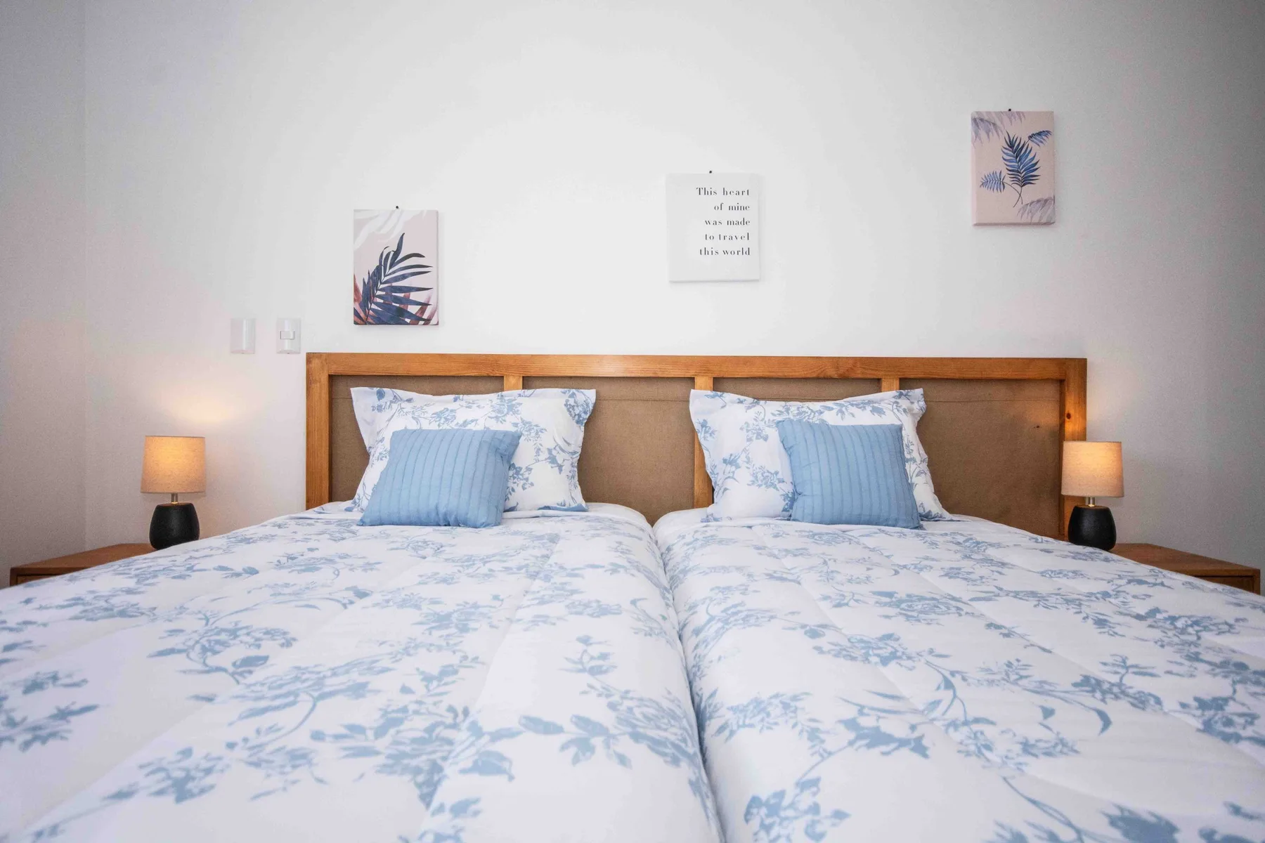Un dormitorio con dos camas vestidas con ropa de cama floral azul.