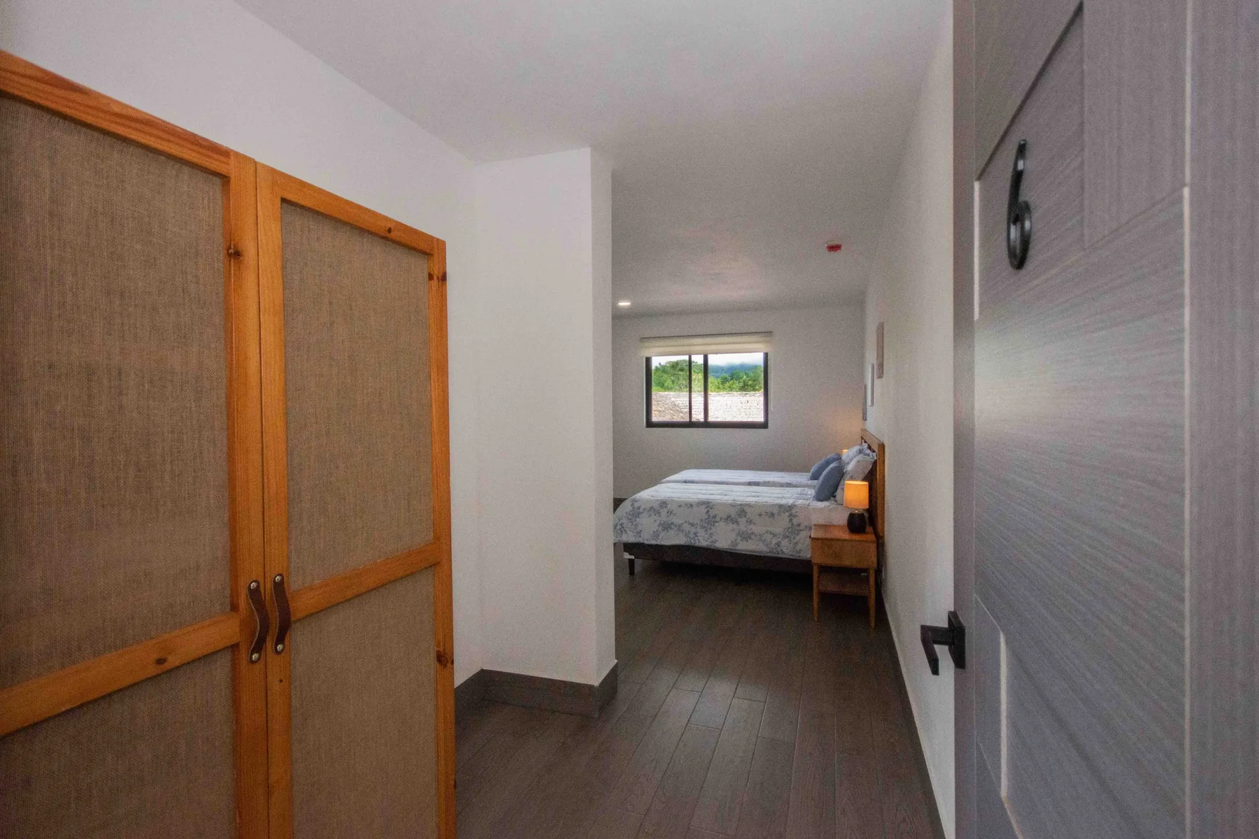 Un dormitorio con una cama bajo una ventana y un armario en primer plano.