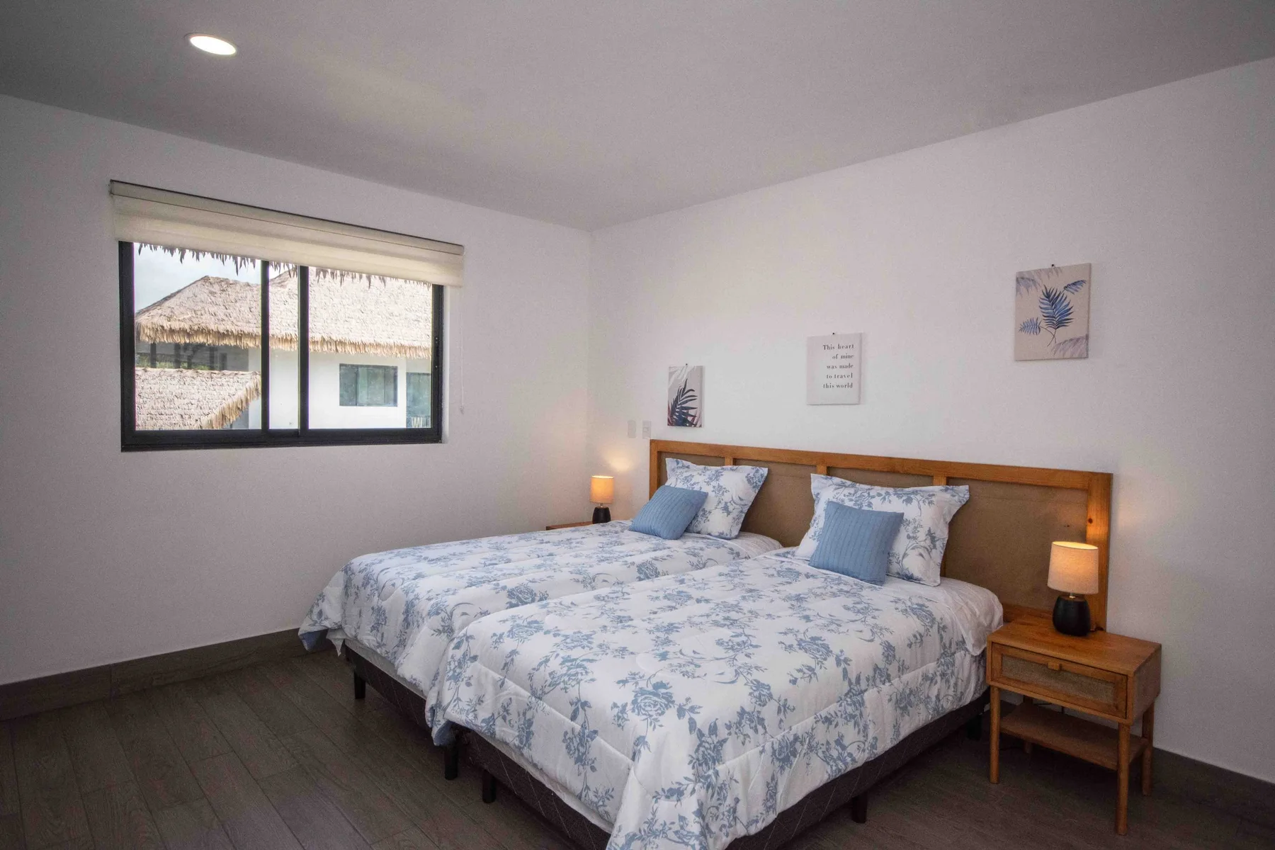 Un dormitorio con una cama cubierta con ropa de cama floral azul y blanca y una ventana.