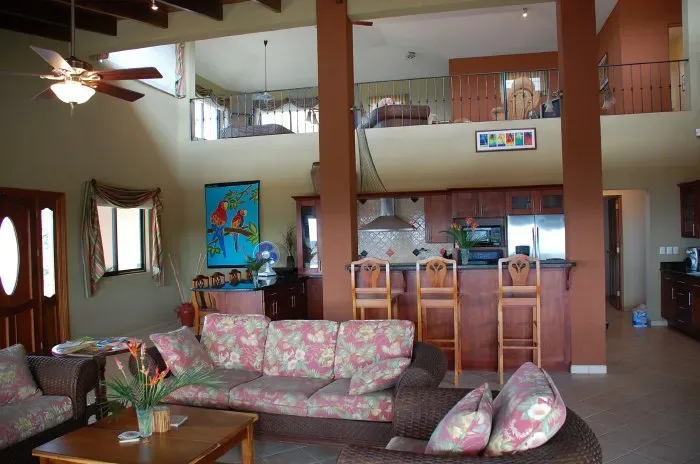 Una amplia sala de estar se abre a una cocina y un balcón en el nivel superior.
