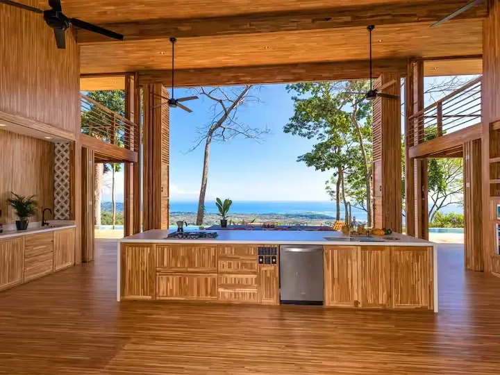 An open-plan kitchen and living area faces a pool and ocean view.