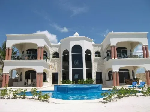 Un gran edificio blanco se alza detrás de una piscina azul.
