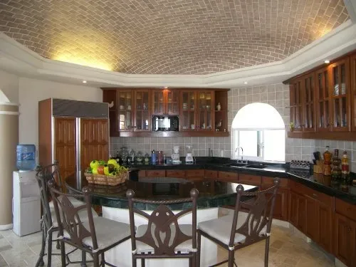 Una cocina con gabinetes de madera, una encimera y una mesa de comedor.