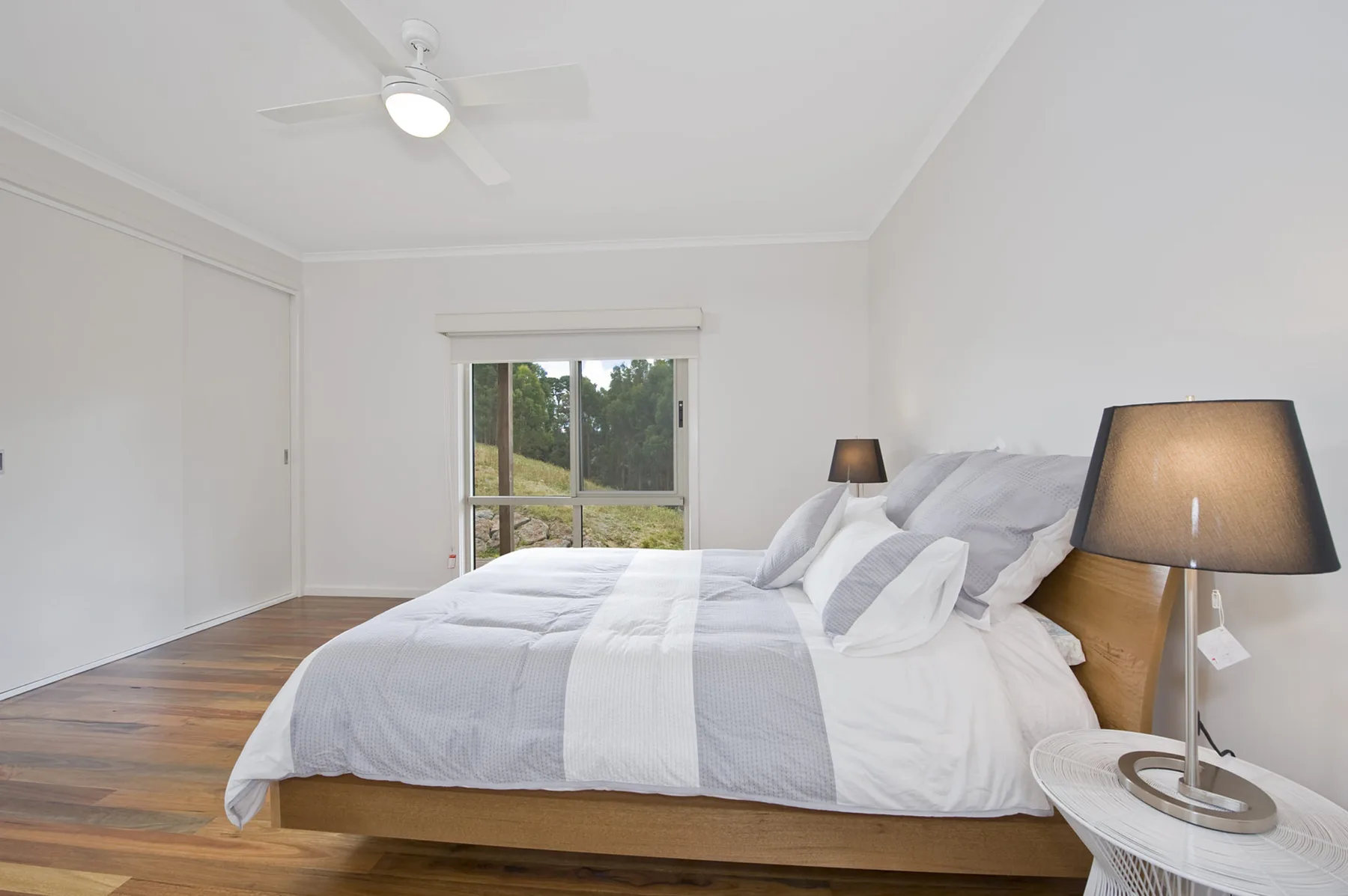 Un dormitorio luminoso con una cama arreglada y puertas corredizas de vidrio.