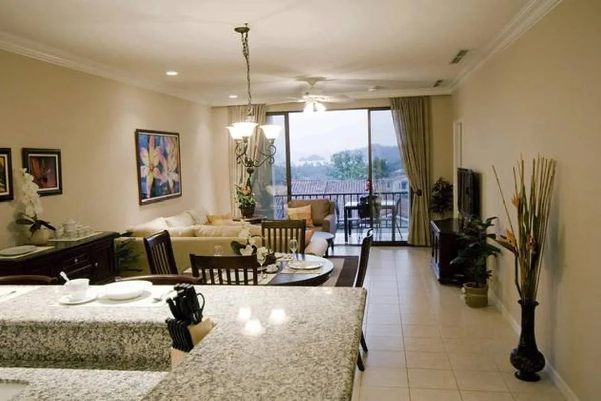 A bright open-plan living and dining area opens onto a balcony through large glass doors.