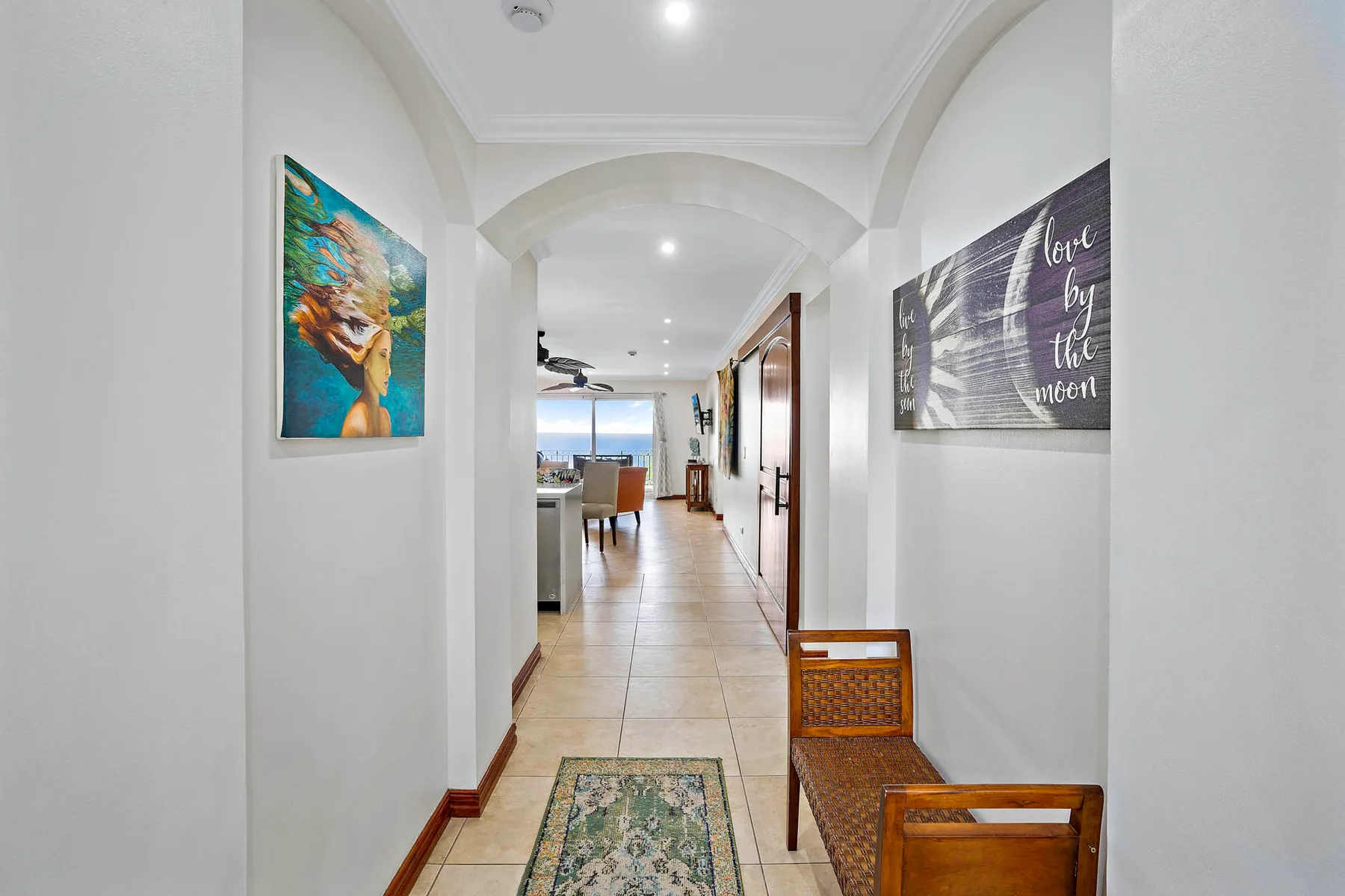 A bright hallway with framed artwork and wooden seating along the wall.