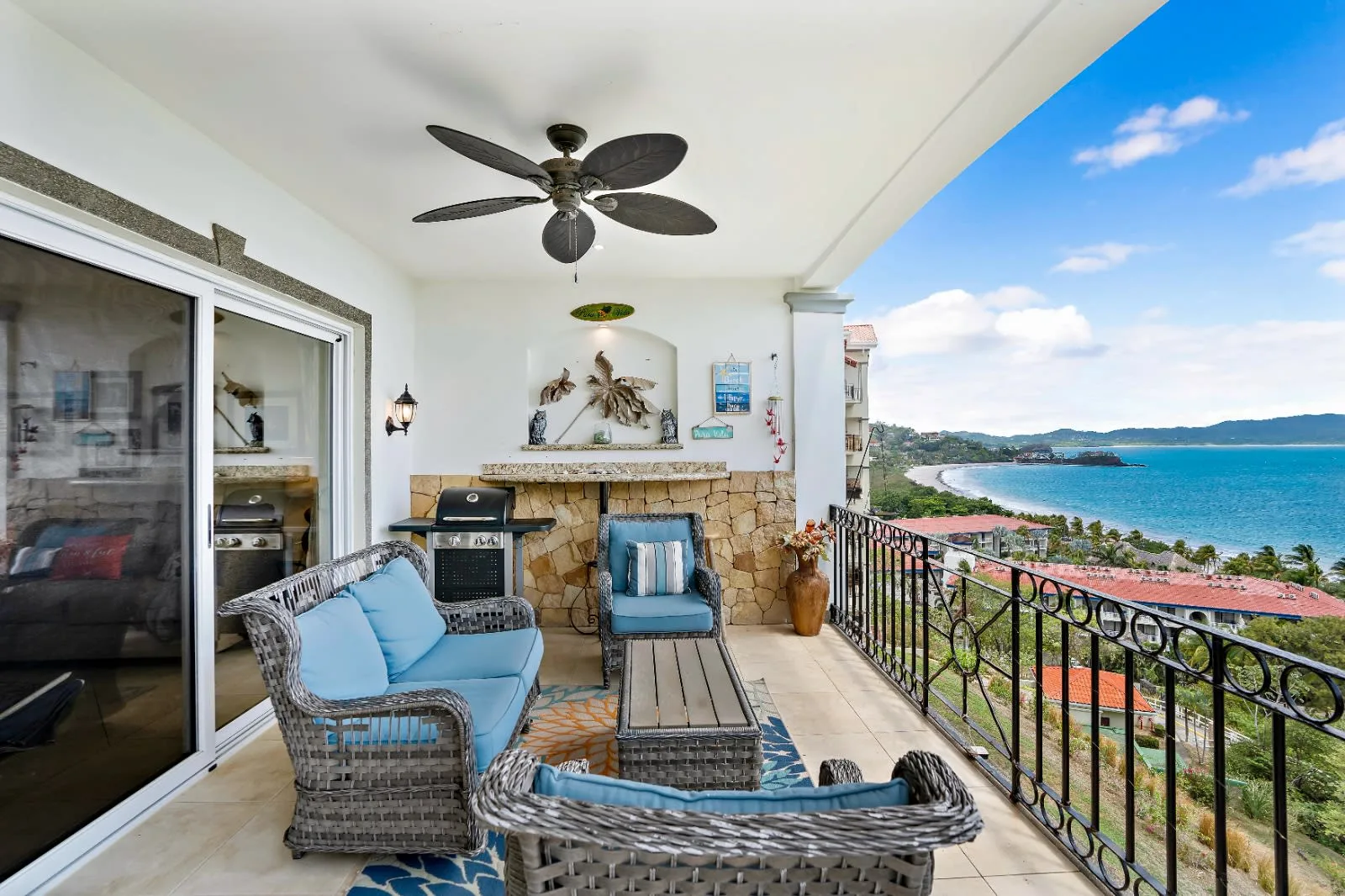 A covered balcony has wicker seating and a view of the bay.