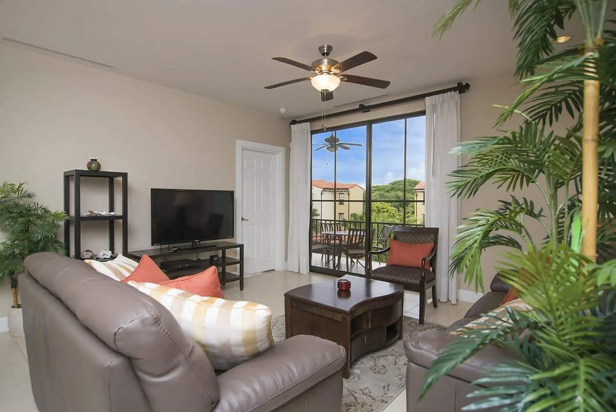 Living room with seating, a television, and glass doors opening onto a patio.