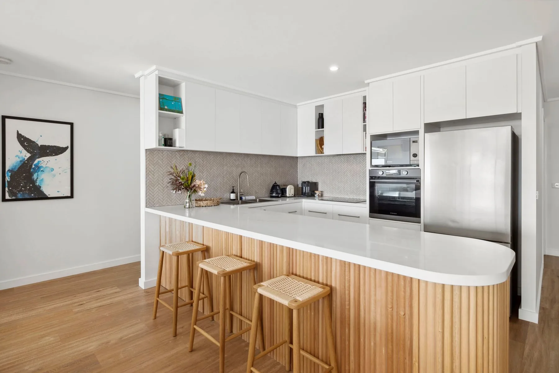 A bright kitchen with white cabinetry, stainless steel appliances, and a wood-fronted island.