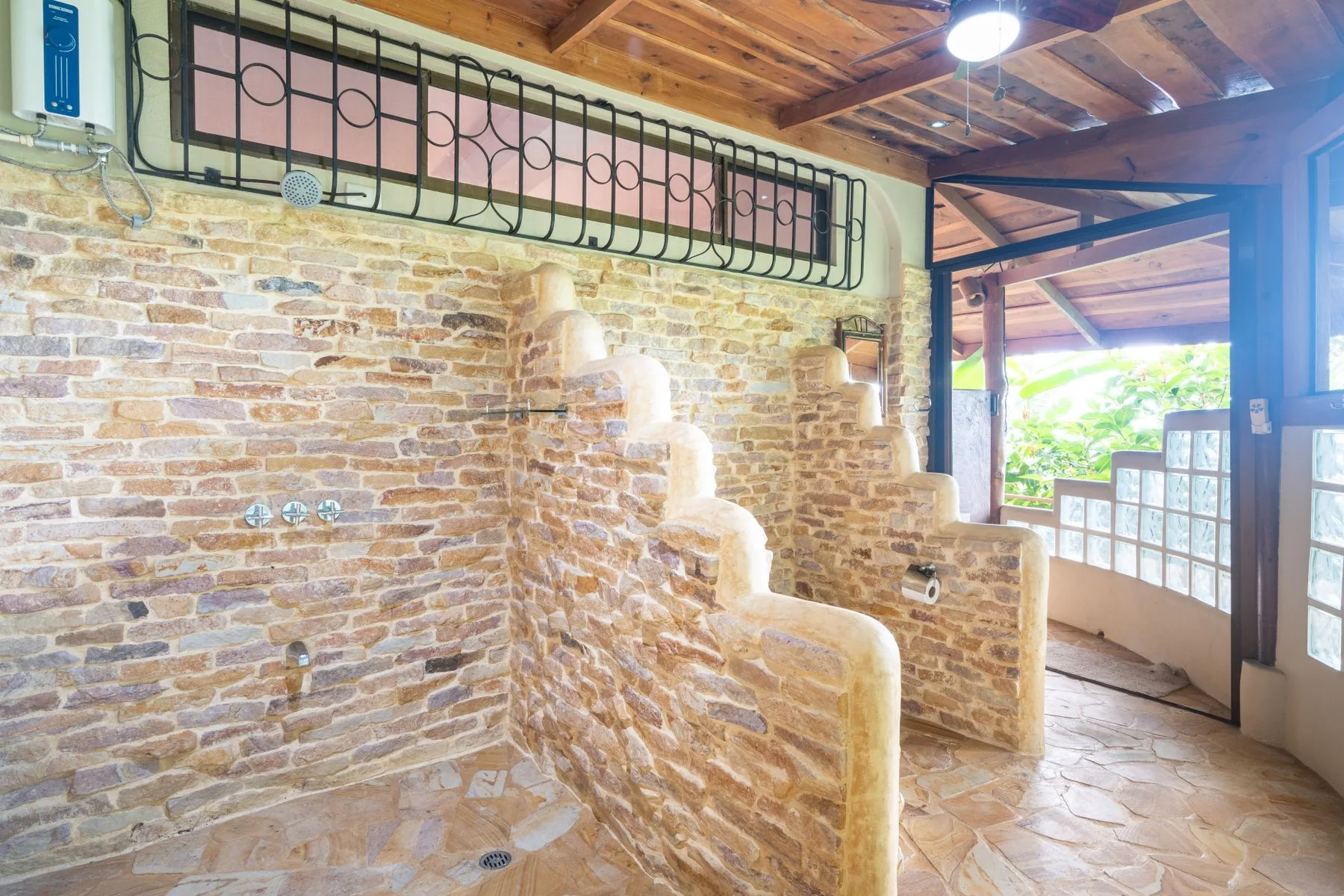 A stone-walled bathroom with a walk-in shower and a wooden ceiling.