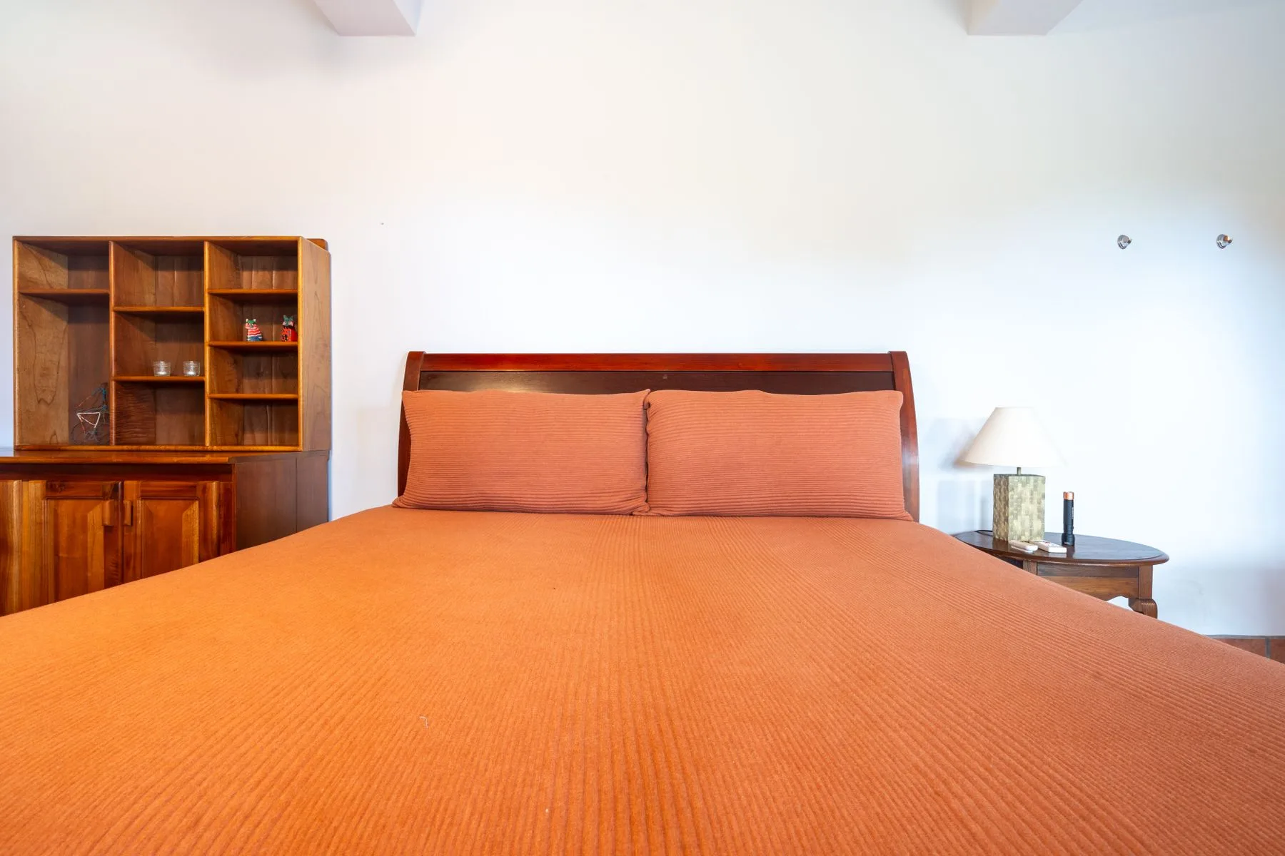 A bedroom with a large bed and wooden shelving against the wall.