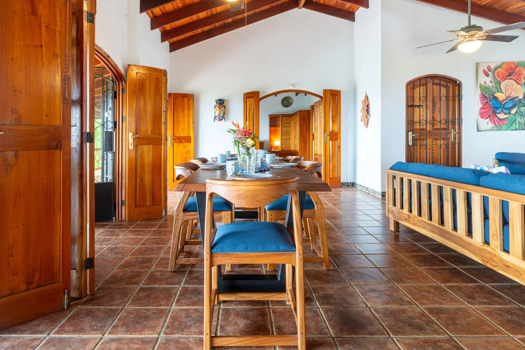 A dining area with a wooden table and chairs beneath a high ceiling.