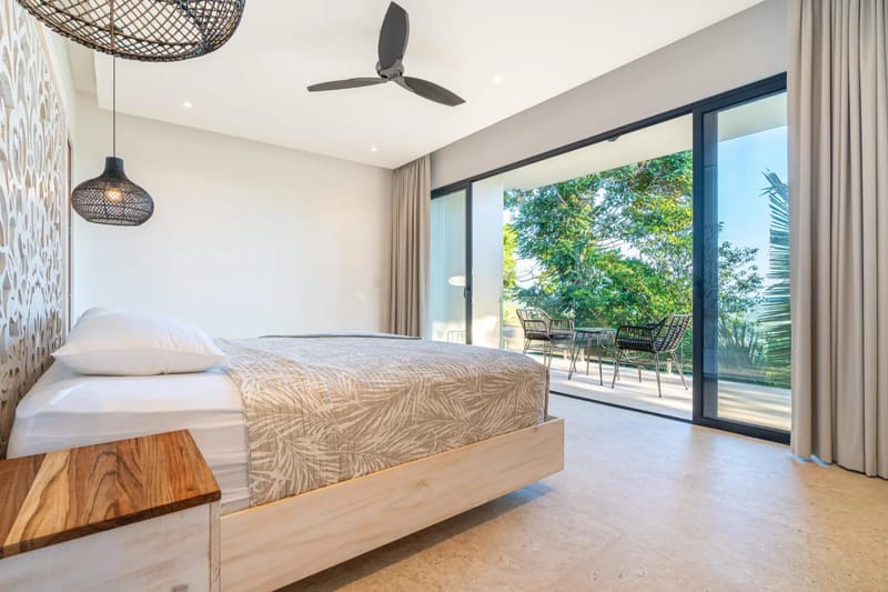 Colíbri Sur · 13. This king bedroom features a carved headboard and glass sliding doors that open to a private terrace overlooking the tropical canopy.