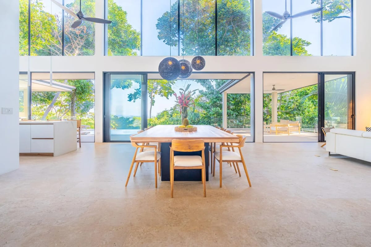 Colíbri Sur · 3. The expansive dining and living area offers abundant natural light and panoramic views of the tropical jungle and distant ocean through floor-to-ceiling glass doors.
