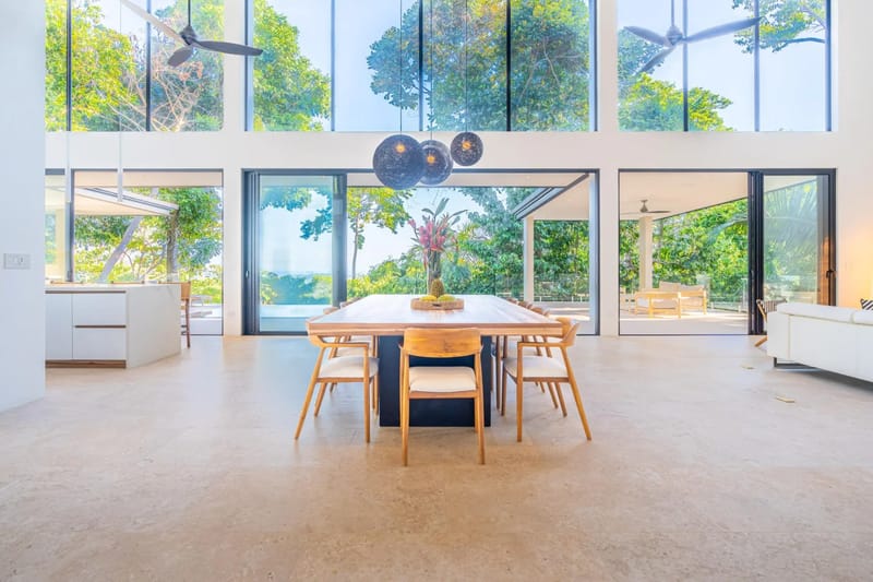 Colíbri Sur · 3. The expansive dining and living area offers abundant natural light and panoramic views of the tropical jungle and distant ocean through floor-to-ceiling glass doors.