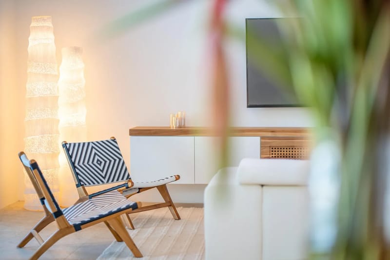 Colíbri Sur · 12. A contemporary living space features modern woven chairs, a wall-mounted media console with a television, and soft ambient floor lighting.
