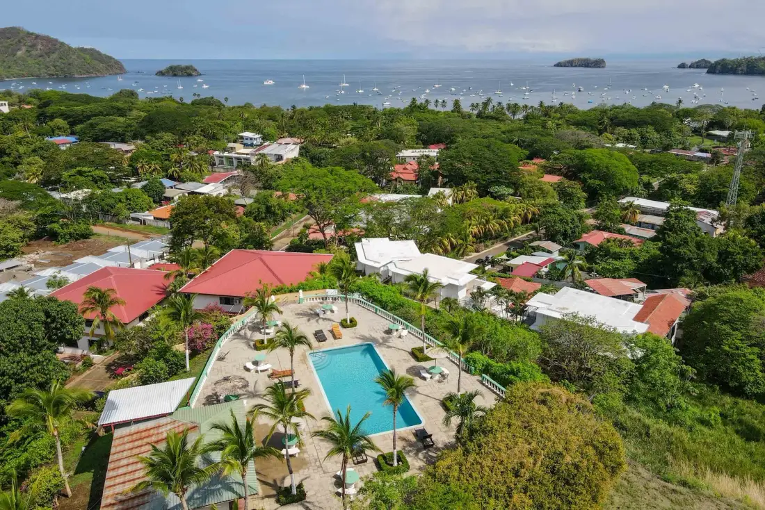 An aerial view of a tropical resort with a pool surrounded by greenery.