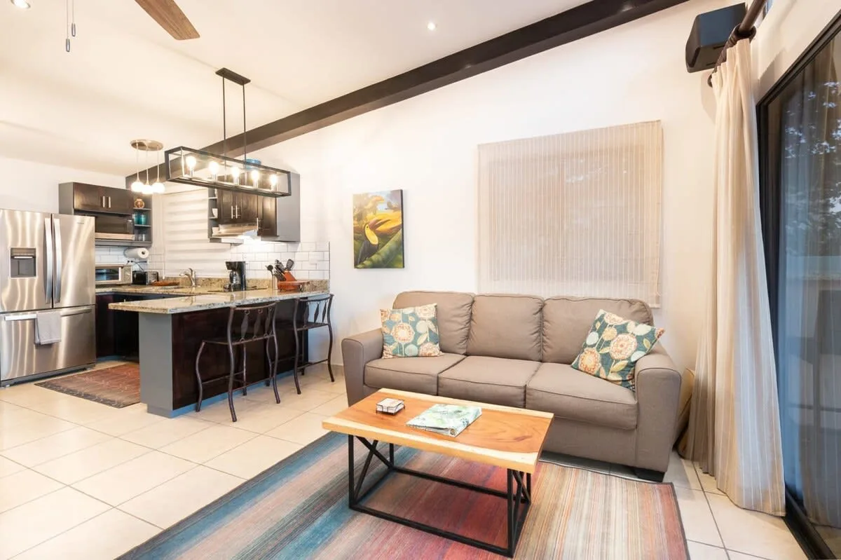 An open-plan living room and kitchen with a sofa and island.
